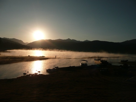 Rising Sun over Lake in Morning with Fog on Waterの写真素材