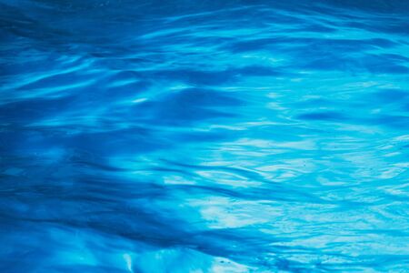 Close-up View of Water Surface over Blue Background in a Swimming Poolの写真素材