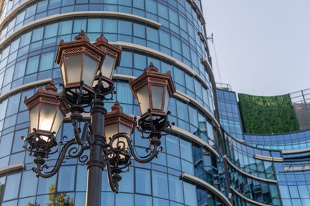 Classic street light pole before a building with glass windows, merging the old with the new