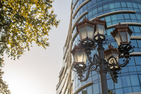 Square lantern before a multi-story office, with a tree silhouette and dusk sky, blending utility and aestheticsの写真素材