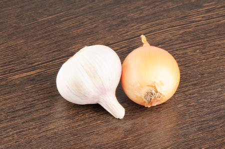 Ripe garlic and onion over blurry brown backgroundの写真素材
