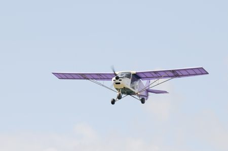 Flying private propeller-driven airplane over blue skyの写真素材