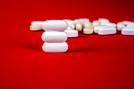 Pills ,tablets and stethoscope on red background. Pharmaceutical medicament, cure in container for health. Antibiotic, painkiller closeup. Copy space for text.の写真素材