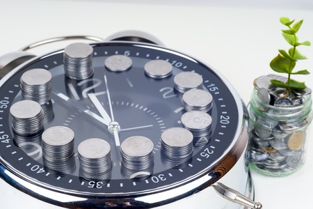 coins with plant and clock, isolated on white background. savings conceptの写真素材