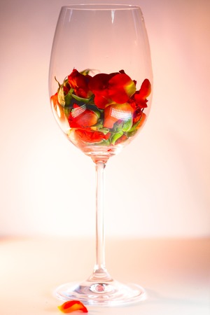 Glass vase filled with red rose petals.の写真素材
