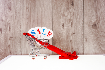 Shopping trolley with gift boxes on a wooden background. Holidays saleの写真素材