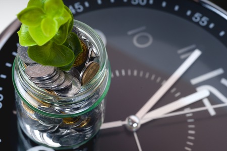 coins with plant and clock, isolated on white background. savings conceptの写真素材