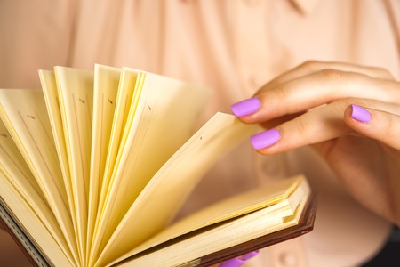 Young girl in a light dress is reading a book. Female hands hold a book in their handsの写真素材