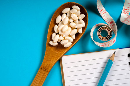 Sheet of Diet Plan and wooden spoon with a measuring tape on a blue background, diet, healthy...