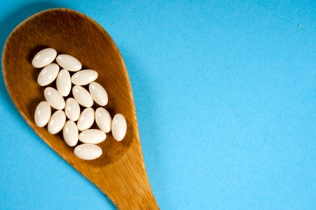 Wooden spoon with a measuring tape on a blue background, diet, healthy lifestyle.の写真素材