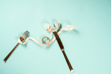 fork and knife with a centimeter on a blue background, diet, healthy lifestyle.の写真素材
