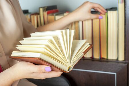 Young girl in a light dress is reading a book. Female hands hold a book in their handsの写真素材