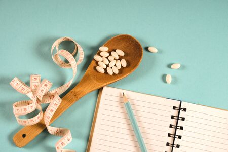 Sheet of Diet Plan and wooden spoon with a measuring tape on a blue background, diet, healthy lifestyle.の写真素材