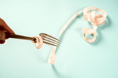 fork and knife with a centimeter on a blue background, diet, healthy lifestyle.の写真素材