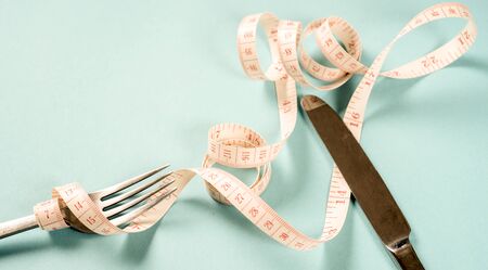 fork and knife with a centimeter on a blue background, diet, healthy lifestyle.の写真素材