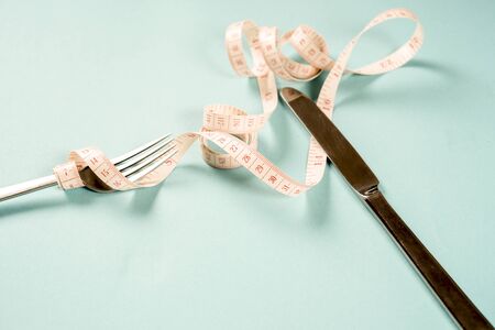 fork and knife with a centimeter on a blue background, diet, healthy lifestyle.の写真素材