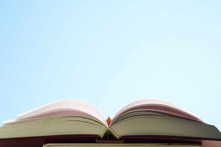 Open book, hardback books on bright colorful background. Blue sky. Back to school. Copy space for text.の写真素材