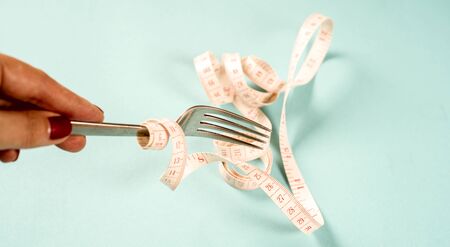 fork and knife with a centimeter on a blue background, diet, healthy lifestyleの写真素材