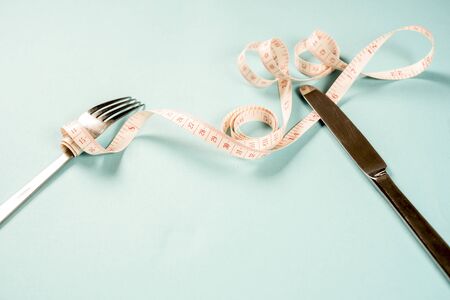 fork and knife with a centimeter on a blue background, diet, healthy lifestyle.の写真素材