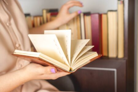 Young girl in a light dress is reading a book. Female hands hold a book in their handsの写真素材