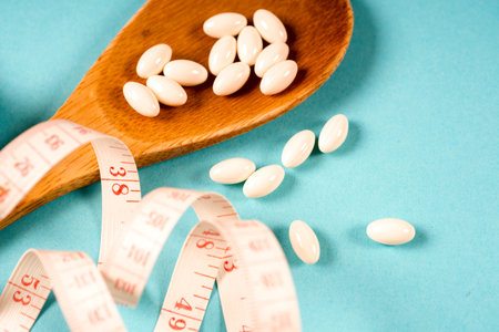 Wooden spoon with a measuring tape on a blue background, diet, healthy lifestyle.の写真素材