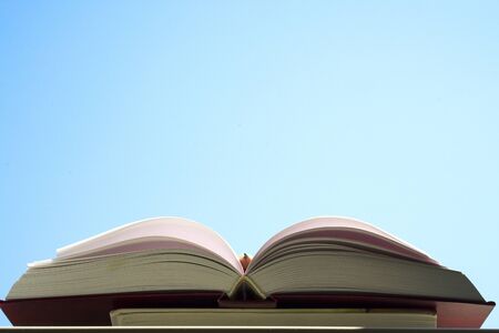 Open book, hardback books on bright colorful background. Blue sky. Back to school. Copy space for text.の写真素材