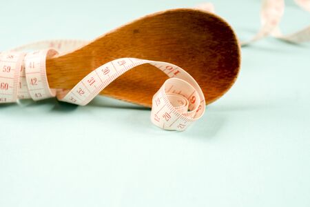 Wooden spoon with a measuring tape on a blue background, diet, healthy lifestyleの写真素材