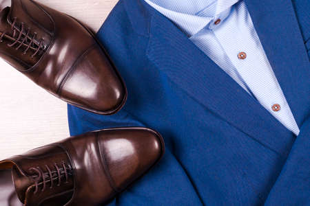 set of classic mens clothes - blue suit, shirts, brown shoes, belt and tie on wooden background.の写真素材