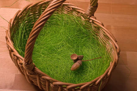 Basket, artificial grass and acorn on a wooden table-top of a tableの写真素材