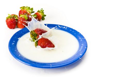 Strawberry falling in dish with milk .の写真素材