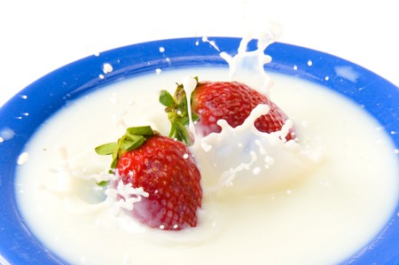 Strawberry falling in dish with milk .の写真素材