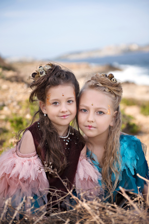portrait of two blonde girls and brunettes in fancy dresses of birds and with nests in hairstylesの写真素材