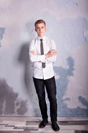 studio portrait of a teenager boy in trousers and a shirt with a tie in indoorsの写真素材