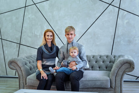 young mother with her two sons sits on a couch indoors