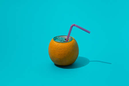 Juicy,refreshing orange with purple straw. summer close up on blue background.minimal composition.の写真素材
