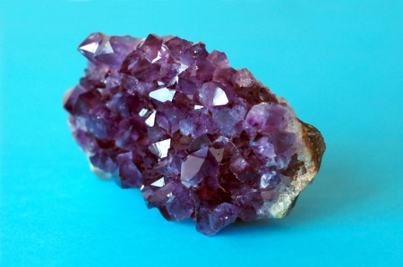Purple unprocessed amethyst crystal on blue backgroundの写真素材