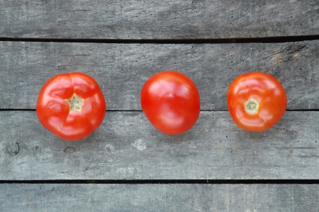 Three tomatoes on gray wooden backgroundの写真素材