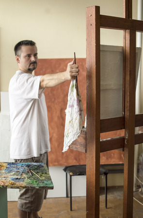 Painter measuring proportions with brush and rag in hand with  thumb method, hand and brush are in center of imageの写真素材