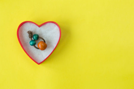 Old handmade ring in opened gift box on yellow paper background with copy space