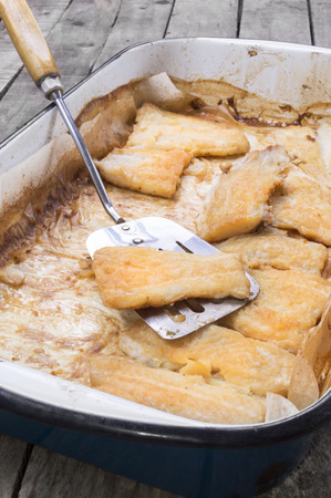 roasted catfish fillets in baking pan on baking paper with serving spoonの写真素材