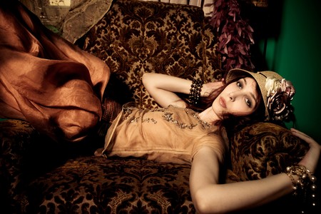 elegant woman with hat lie in armchair, indoor shotの写真素材