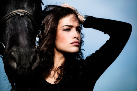 beautiful black hair woman and black horse outdoor day shotの写真素材