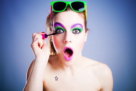 funny young woman applying mascara studio shotの写真素材