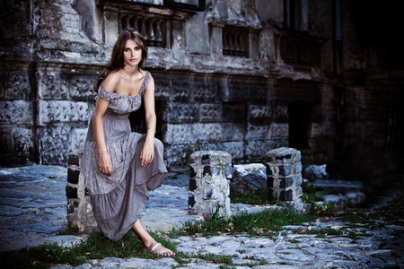 young woman in front of old stone house, outdoor portrait at duskの写真素材
