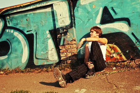 young man sitting by the graffiti wall, summer dayの写真素材