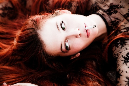 beautiful redhead woman portrait with cigaretteの写真素材