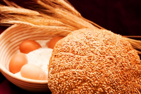 sesame bread with flour, eggs and wheat in backgroundの写真素材