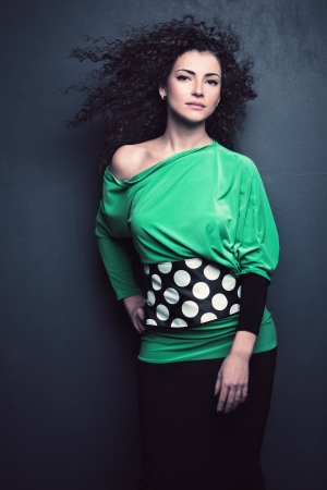 curly hair beautiful young woman in elegant green dress studio shotの写真素材