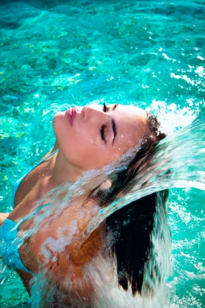 attractive young woman refresh in pool under the small waterfallの写真素材