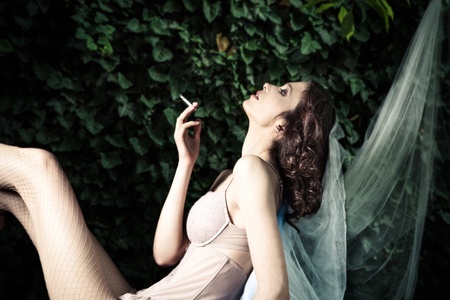 fashion  woman in garden smoking,  side viewの写真素材